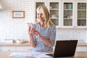 Smiling middle aged woman using smartphone for payment utility bill